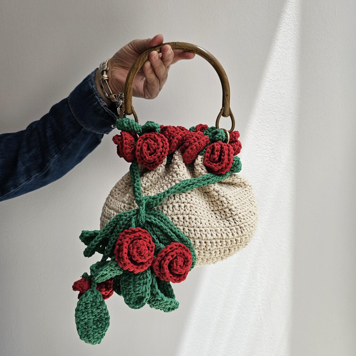 Cream Hand-Crocheted Drawstring Bucket Pouch With Draping Red Rose And Green Vine Bouquet Appliqué, Curved Natural Wooden Ring Fixed Top Handle Hardware