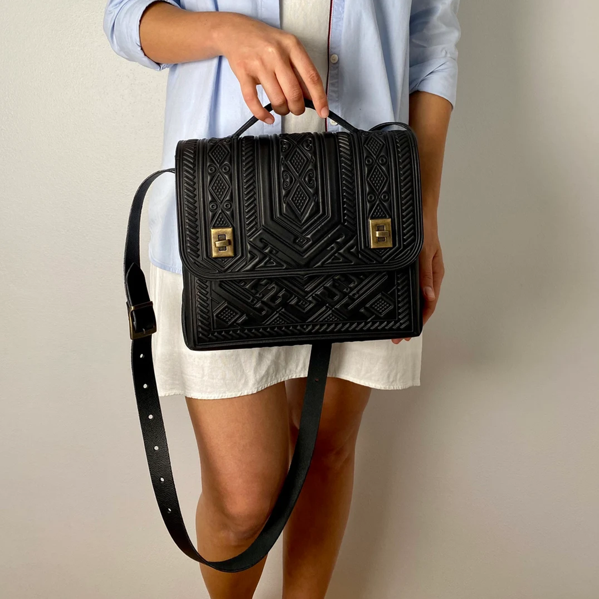 Deep Black Embossed Tribal Geometric Structured Rectangular Satchel With Curved Fixed Top Handle, Punch-Hole Shoulder Strap And Dual Antique Brass Turn-Lock Flap Fastener Hardware Leather Bag