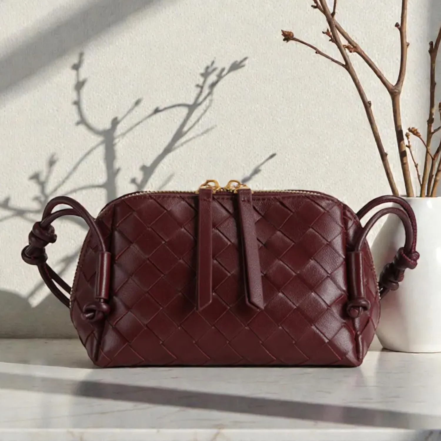 Multi-Tone Uniform Diamond Grid Woven Compact Rectangular Pouch With Knotted Side Loop Carry Strap And Dual Gold Pull Top Zipper Closure Hardware Leather Bag