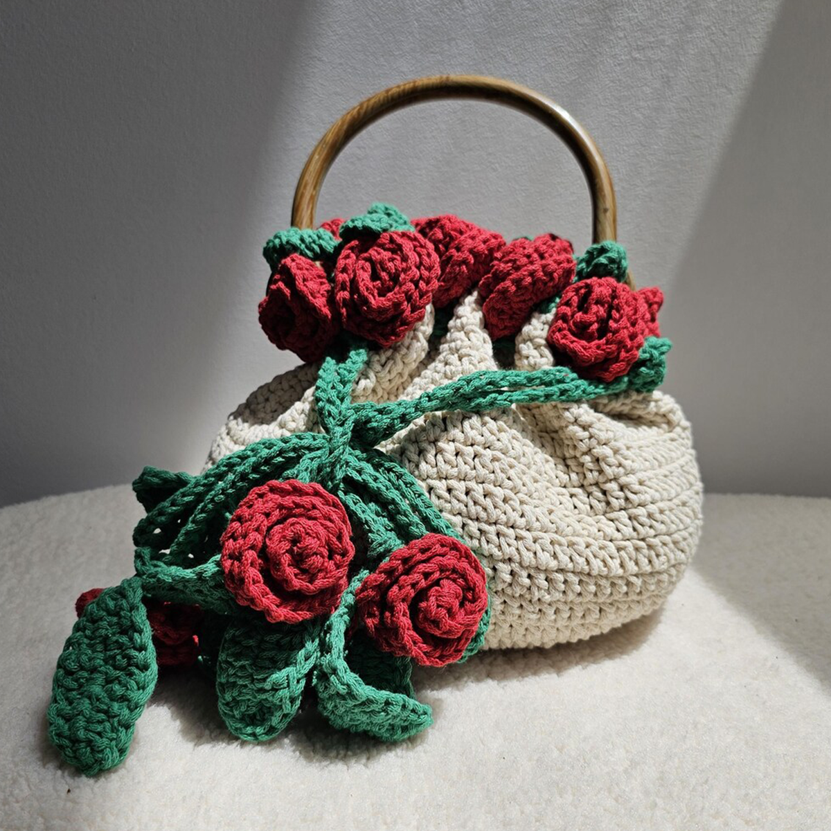 Cream Hand-Crocheted Drawstring Bucket Pouch With Draping Red Rose And Green Vine Bouquet Appliqué, Curved Natural Wooden Ring Fixed Top Handle Hardware