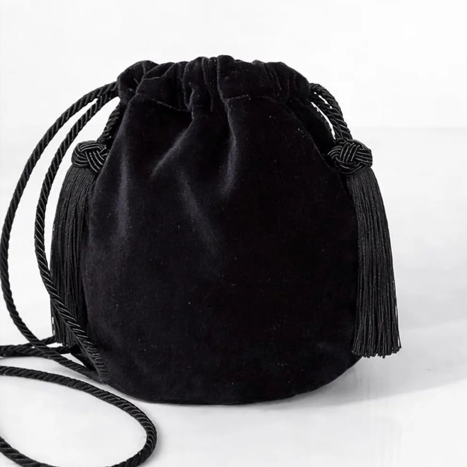 Matte Black Velvet Rounded Drawstring Bucket Pouch With Knotted Cord Side Tassel Accents And Continuous Twisted Woven Cord Shoulder Carry Strap